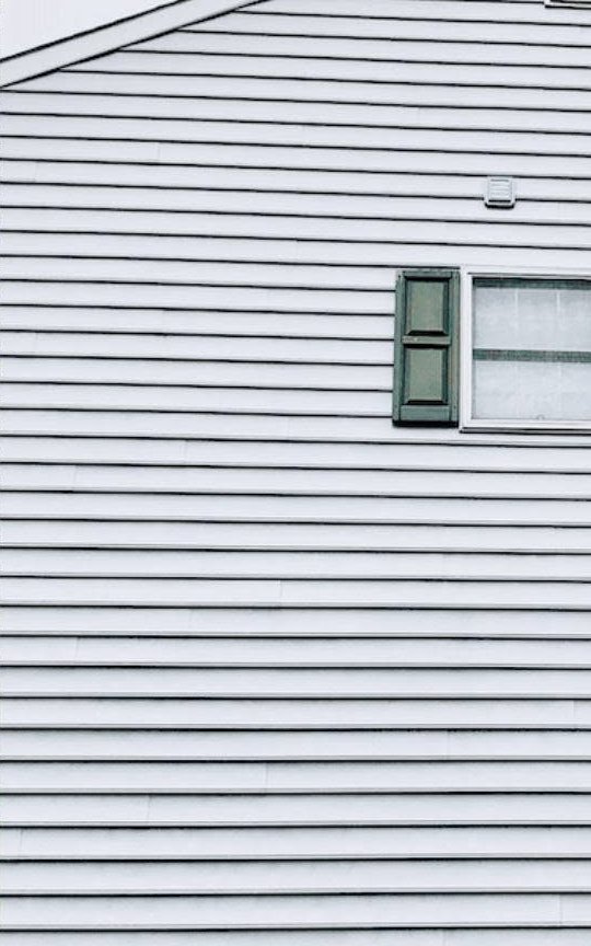 White horizontal siding on residential building with green shutters and window